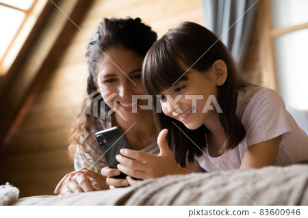 Smiling Latin 7s girl using smartphone under mom control 83600946
