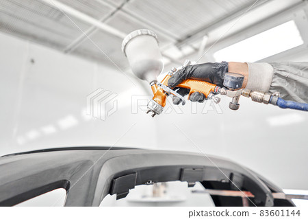 Paint Gun is designed by professionals for a professional quality paint job. Worker painting parts of the car in special painting chamber, wearing costume and protective gear. Car service station. Paint Gun is designed by professionals for a professional quality paint job. Worker painting parts of the car in special painting chamber, wearing costume and protective gear. Car service station. 83601144
