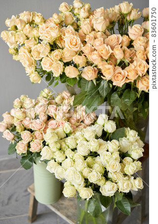 Floral carpet, flower texture, shop concept. Beautiful fresh blossoming flowers roses, spray roses. Blossom of pastel color in vases and pails. Top view. 83601750