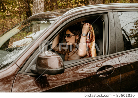 A young beautiful girl in a headscarf is sitting in an expensive brown car. A young beautiful girl in a headscarf is sitting in an expensive brown car. 83601830