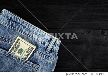 Pocket money. Dollar in hip pocket of worn blue jeans. Close-up. 83603990