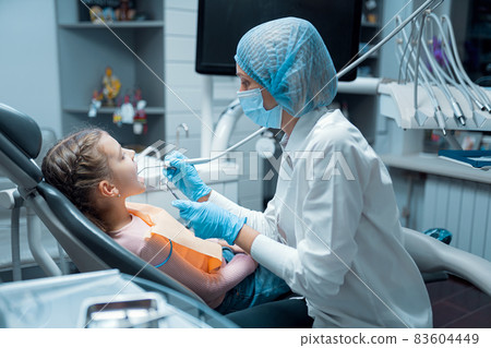 Female dentist treats teeth of little girl patient at dental clinic. Dentistry concept  83604449