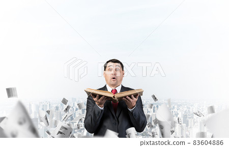 Surprised businessman holding open book Surprised businessman holding open book 83604886