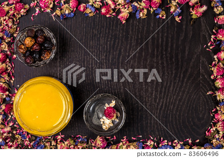 Organic honey in a small jar, mud and clay powder on wooden background. Frame of dried flowers Organic honey in a small jar, mud and clay powder on wooden background. Frame of dried flowers 83606496