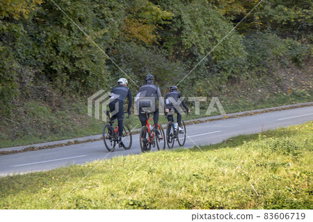 Group athletes cyclists riding a bike uphill along a road 83606719