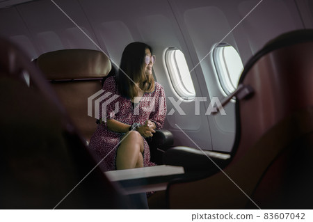 woman sitting beside plane window and lookint through out with smiling face 83607042