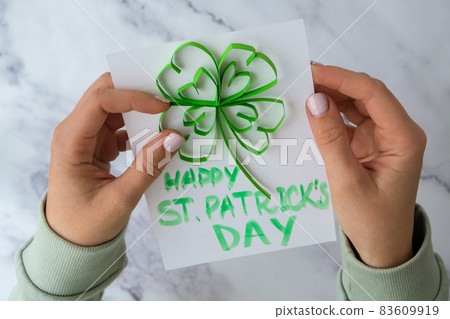 Diy St. Patricks Day greeting card made of Quilling and paper clovers on white background. Gift idea, decor Spring, happy Patrick Day. Step by step. Diy St. Patricks Day greeting card made of Quilling and paper clovers on white background. Gift idea, decor Spring, happy Patrick Day. Step by step. 83609919
