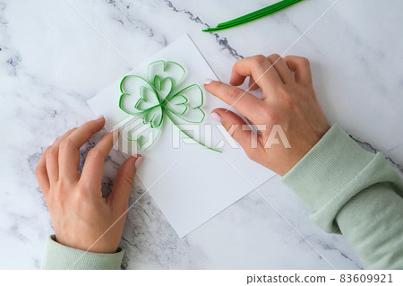 Diy St. Patricks Day greeting card made of Quilling and paper clovers on white background. Gift idea, decor Spring, happy Patrick Day. Step by step. 83609921