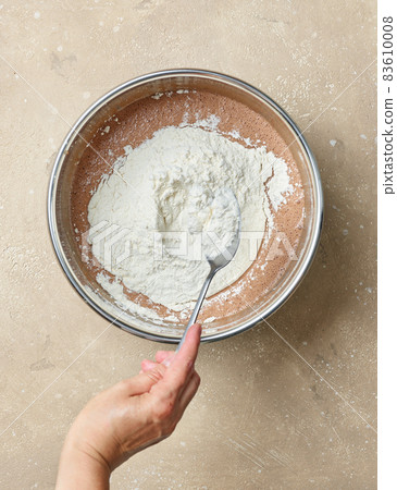 add flour to the bowl of chocolate cake dough add flour to the bowl of chocolate cake dough 83610008