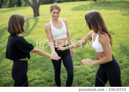 Girls with fitness mats bumping fists on meadow Girls with fitness mats bumping fists on meadow 83610558
