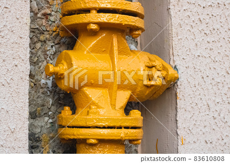 Yellow water pipe on a house wall 83610808