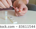 The woman takes a blood sample with a pipette from his finger 83611544
