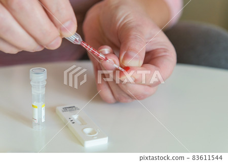 The woman takes a blood sample with a pipette from his finger The woman takes a blood sample with a pipette from his finger 83611544