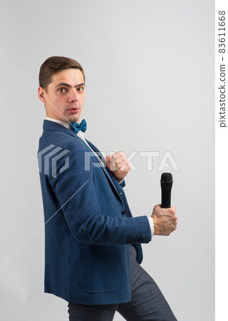 The entertainer. Young elegant talking man holding microphone, Isolated in studio. The entertainer. Young elegant talking man holding microphone, Isolated in studio. 83611668