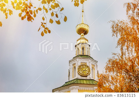 Ancient christian church and autumn yellow trees. Beautiful domes, high bell tower against the sky Ancient christian church and autumn yellow trees. Beautiful domes, high bell tower against the sky 83613115
