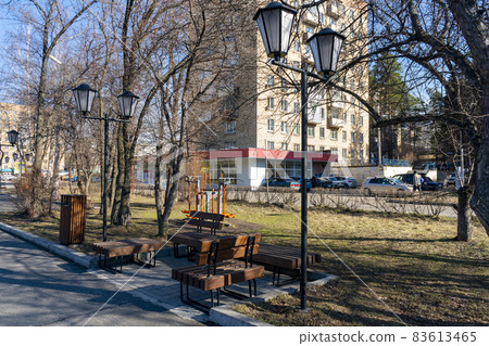 Wooden benches along the alley with lanterns in the park. Wooden benches along the alley with lanterns in the park. 83613465