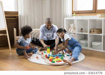 Smiling caring young african american father playing toys with kids. 83614776