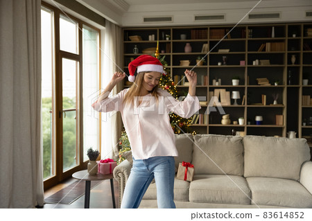Happy Xmas girl in Santa Claus hat dancing at home 83614852