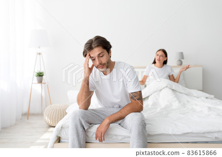 Angry resentful upset millennial caucasian wife sits on bed, quarreling husband, shouting and dispute Angry resentful upset millennial caucasian wife sits on bed, quarreling husband, shouting and dispute 83615866