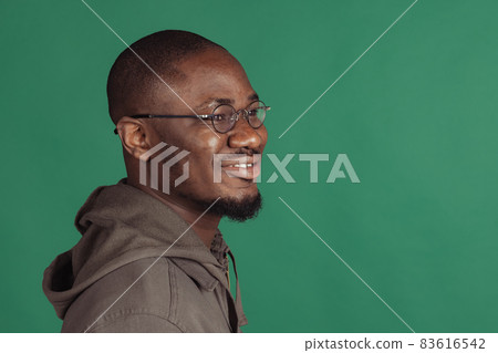 Side view. Close-up portrait of young african man posing isolated on studio background with copyspace for ad. Side view. Close-up portrait of young african man posing isolated on studio background with copyspace for ad. 83616542