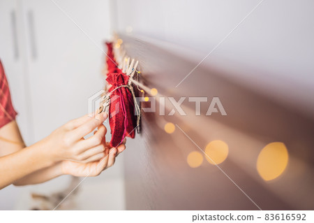 Woman making Christmas advent calendar. Pouches on a rope 83616592