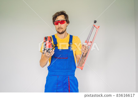 A tiler, a tiling specialist, holds a tile cutter in his hands 83616617