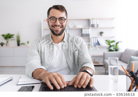 Cheerful mature caucasian guy in glasses working on laptop or have online meeting on living room interior 83616618