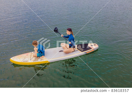 Mother and son paddling on stand up board having fun during summer beach vacation Mother and son paddling on stand up board having fun during summer beach vacation 83618357