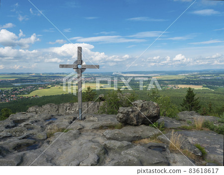 Tempelwand sandstone viewpoint with wooden cross next to hill Topfer near Oybin with view of Zittau town and Poland German borders in Zittauer Gebirge mountains, Saxony, germany. Summer sunny day 83618617