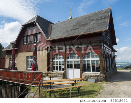 Old rustic building of Topferbaude viewpoint restaurant and hut next to hill Topfer near the town of Oybin at Zittauer Gebirge mountains nature park in Saxony, germany. Summer sunny day Old rustic building of Topferbaude viewpoint restaurant and hut next to hill Topfer near the town of Oybin at Zittauer Gebirge mountains nature park in Saxony, germany. Summer sunny day 83618621