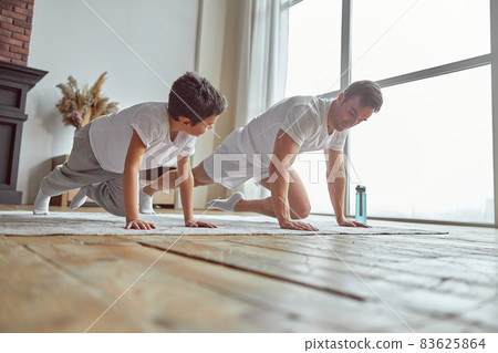 Little boy doing plank with dad indoors 83625864