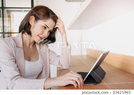 Happy working woman is using a tablet in the office. Happy working woman is using a tablet in the office. 83625965