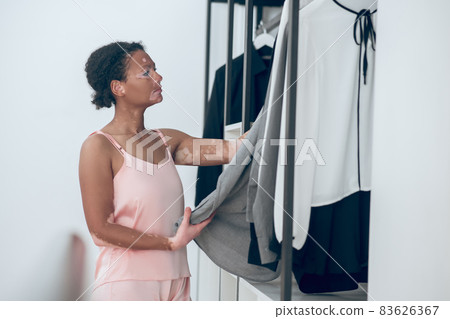 A pretty young female choosing clothes from her wardrobe 83626367