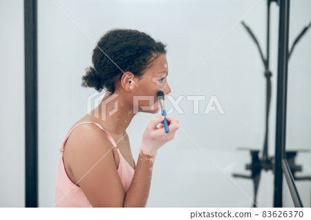 A pretty curly-haired woman doing make and looking pleased 83626370