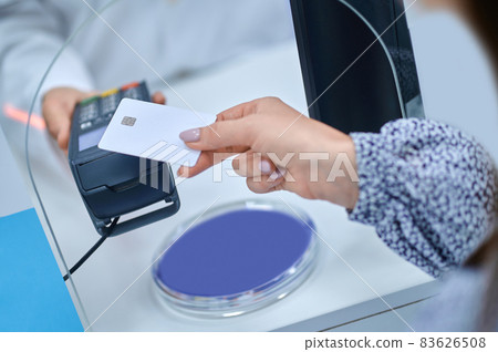 Womans hand bringing credit card to pos terminal Womans hand bringing credit card to pos terminal 83626508