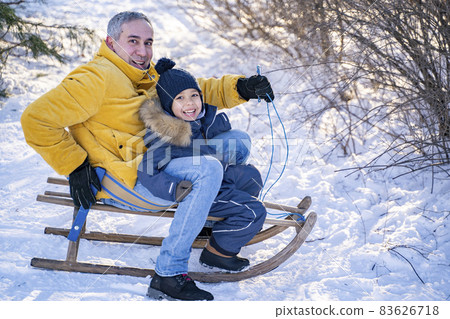 Father and his little afro american or latin son slide down the snowy mountain Father and his little afro american or latin son slide down the snowy mountain 83626718
