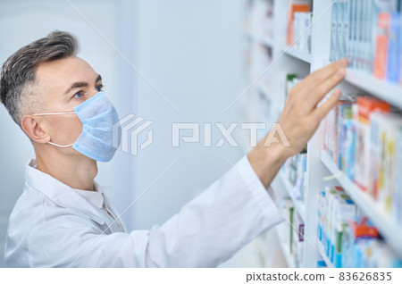 Male pharmacist looking for medicine on shelf 83626835