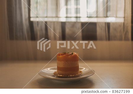 Orange fruit cake in a cup served on white dish. 83627199