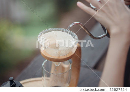 Hand drip coffee, Barista pouring the hot water in the filter before pouring the coffee beans step. Hand drip coffee, Barista pouring the hot water in the filter before pouring the coffee beans step. 83627834
