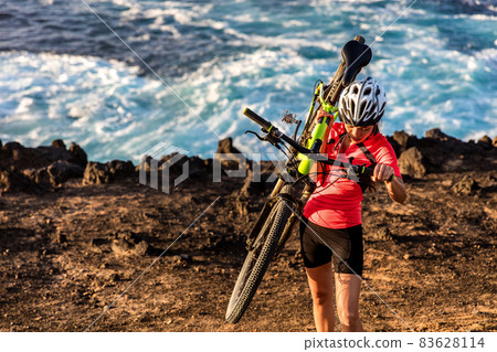 Mountain biking carrying bike uphill walking up hill. MTB biker cyclist riding outdoors. Cycling sports. Mountain biking carrying bike uphill walking up hill. MTB biker cyclist riding outdoors. Cycling sports. 83628114