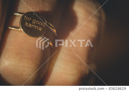 Gold ring engraved: For good karma. A gold ring on the finger of the hand close-up. Selective focus, defocused, blur 83628629