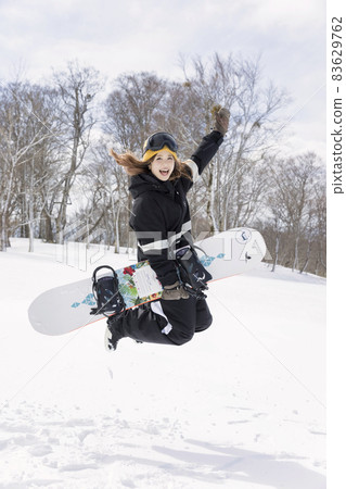 在滑雪勝地跳躍的年輕女子 83629762