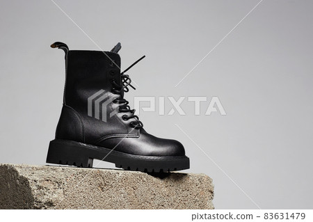 Black boot on a cinder block. fashion shoes still life 83631479