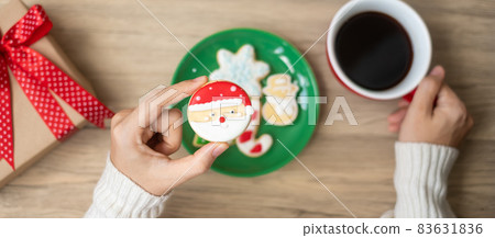Merry Christmas with woman hand holding coffee cup and homemade cookie on table. Xmas eve, party, holiday and happy New Year concept Merry Christmas with woman hand holding coffee cup and homemade cookie on table. Xmas eve, party, holiday and happy New Year concept 83631836