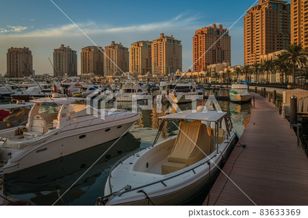 Porto Arabia Marina in The pearl Doha, Qatar sunset shot showing luxurious yachts docked at the marina with residential buildings in background. Porto Arabia Marina in The pearl Doha, Qatar sunset shot showing luxurious yachts docked at the marina with residential buildings in background. 83633369