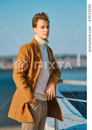 Young man in checkered trousers, sweater and wool coat outdoor Young man in checkered trousers, sweater and wool coat outdoor 83633898