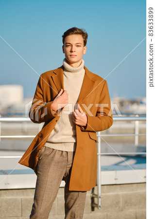 Young man in checkered trousers, sweater wraps wool coat outdoor Young man in checkered trousers, sweater wraps wool coat outdoor 83633899