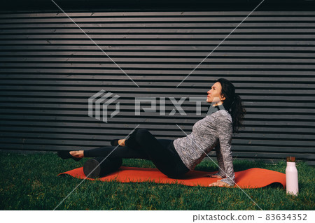 Young fit woman exercising butt using foam roller at gym Young fit woman exercising butt using foam roller at gym 83634352