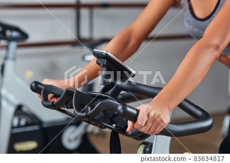 Woman hands on a bar stationary bike the gym 83634817
