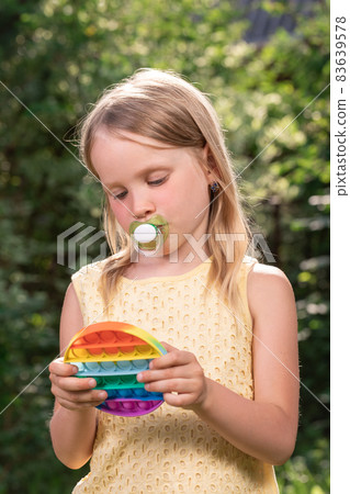 Child plays popit fidget toy outdoors Child plays popit fidget toy outdoors 83639578